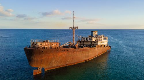 Free A majestic rusty shipwreck floating in the tranquil blue waters of Lanzarote at sunset. Stock Photo