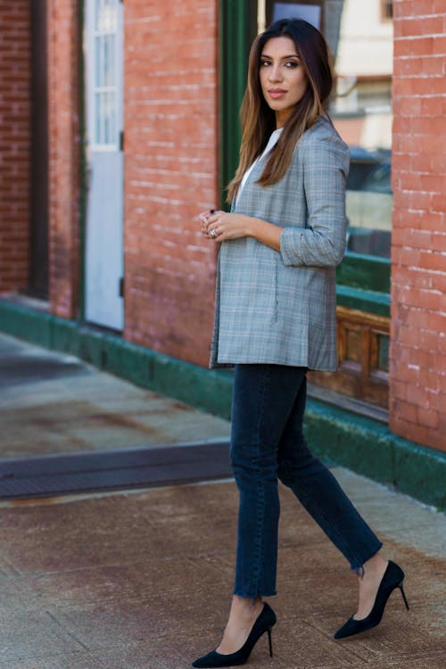 Woman Wearing a Coat Walking on a Sidewalk