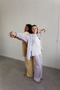 Man in White Dress Shirt and White Pants Standing Beside Woman in White Long Sleeve Shirt