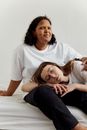Woman in White Crew Neck T-shirt and Blue Denim Jeans Sitting Beside Girl in White