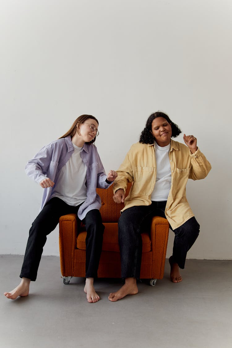 Two Women Sitting On A Chair Dancing