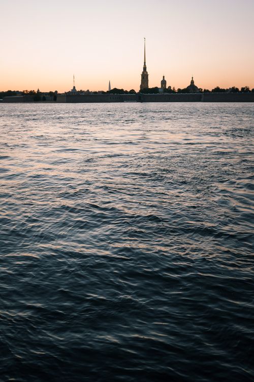 Free Beautiful sunset view with Peter and Paul Fortress silhouetted against calm waters. Stock Photo