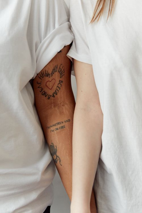 Free Two people wearing white shirts interlocking arms, showing tattoos. Stock Photo