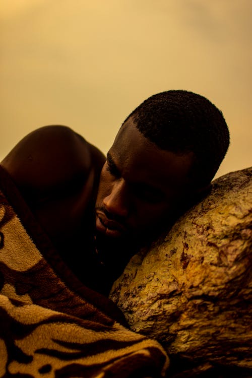 Photo of a Man Sleeping on a Rock
