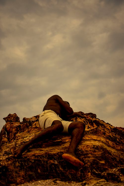 A Shirtless Man Lying on a Rock