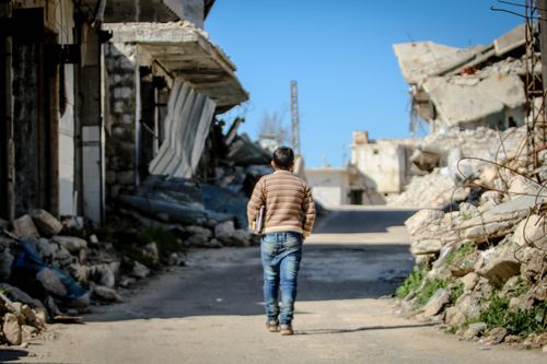 Free A young boy walks through the demolished streets of Idlib, Syria, amidst the rubble and destruction. Stock Photo