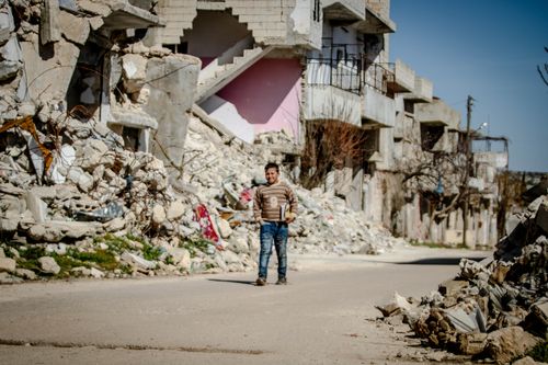 Free A person walks through the ruins of buildings in Idlib, capturing the impact of conflict. Stock Photo
