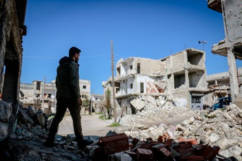 Free A man walks through the rubble of destroyed buildings in Idlib, Syria, highlighting urban devastation. Stock Photo