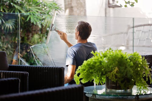灰色襯衫清洗沙發附近的透明玻璃牆的男人