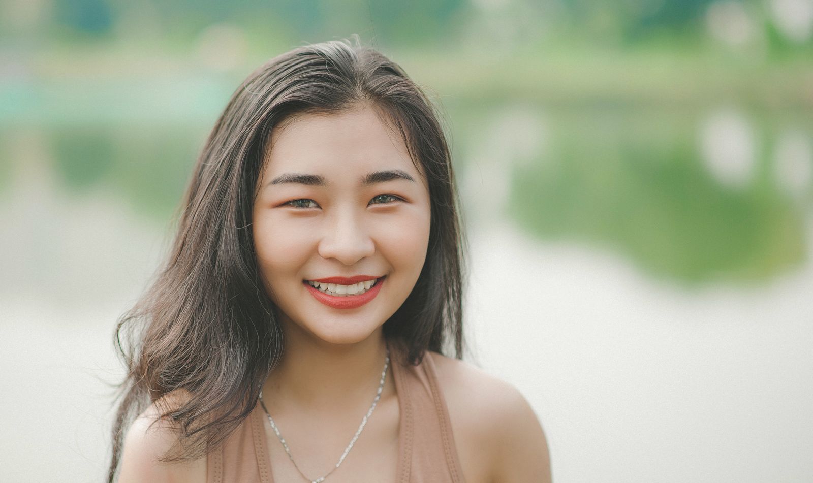 Mariana sorrindo naturalmente ao ar livre, próxima a um lago