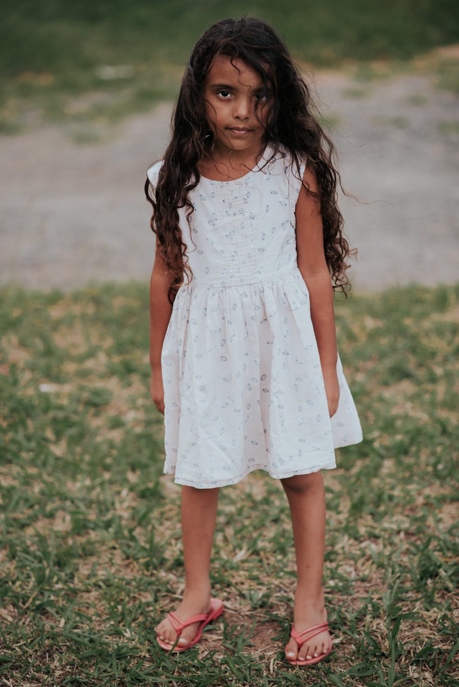 Girl in a breezy printed cotton day dress standing near a riverside