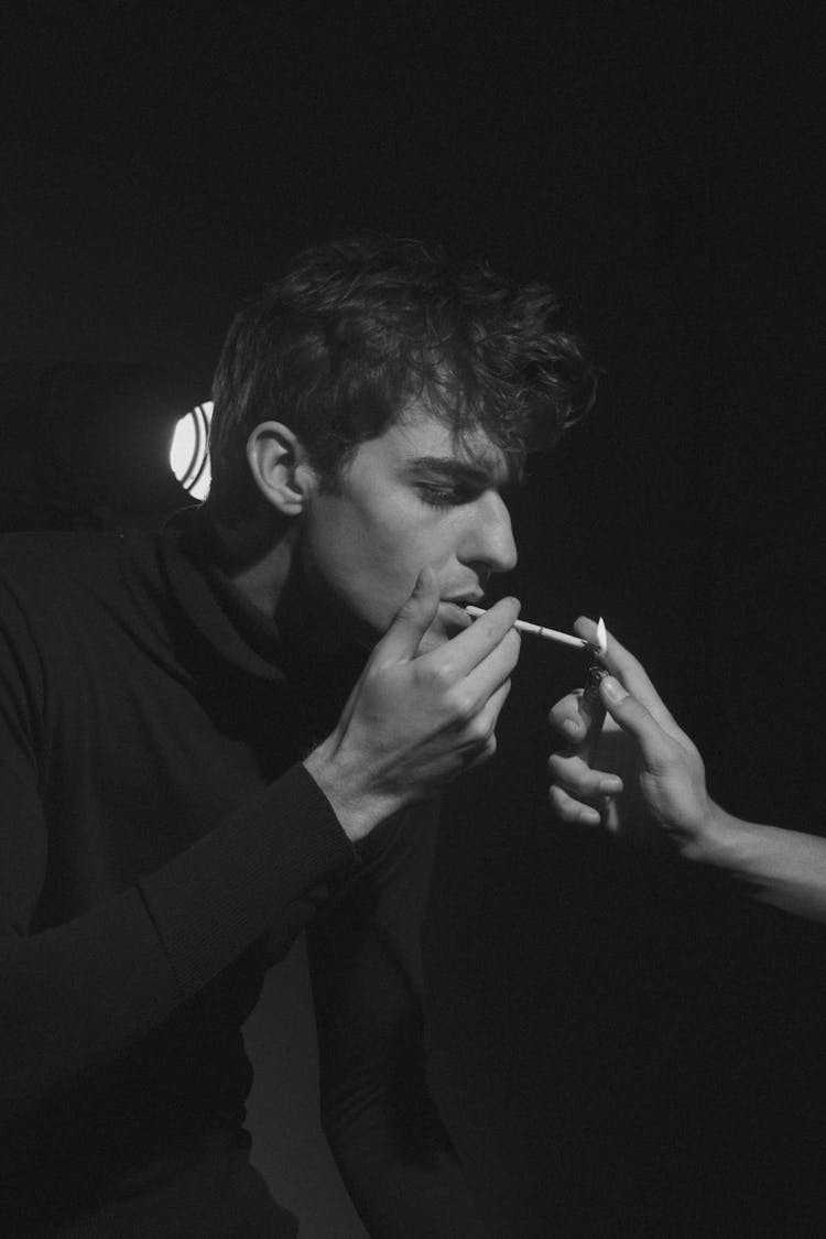 Grayscale Photo Of A Man Lighting A Cigarette