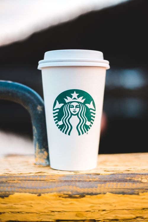 Free A closeup of a coffee cup placed on a wooden surface, capturing a serene outdoor ambiance. Stock Photo