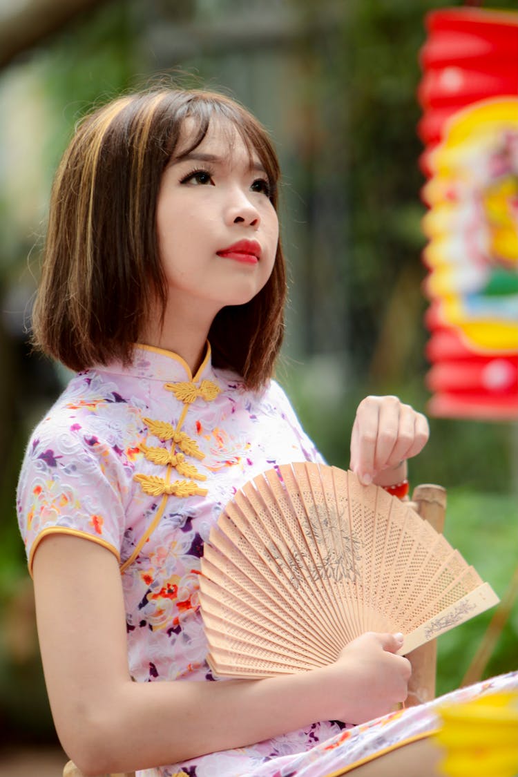 A Young Woman In A Cheongsam Holding A Hand Fan