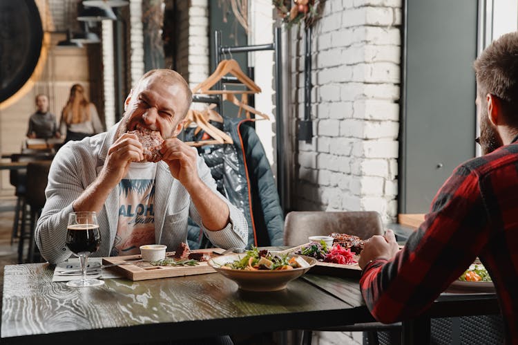 A Man Eating A Piece Of Steak