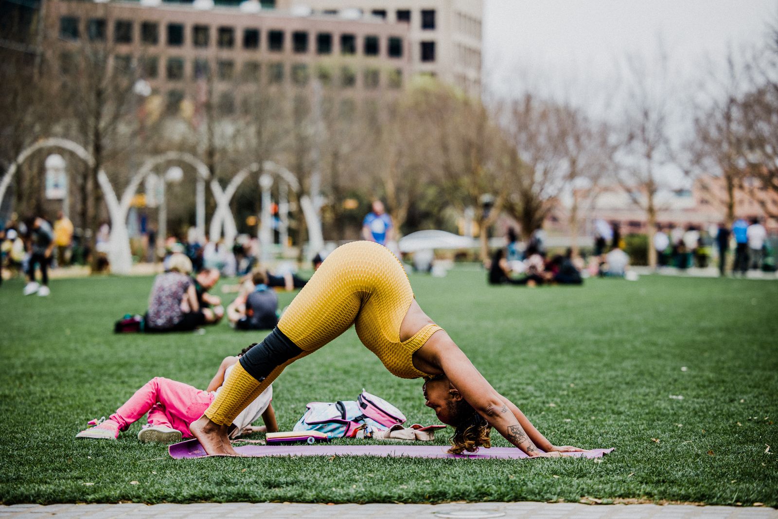Pregnant woman practicing downward dog yoga pose outdoors in a park