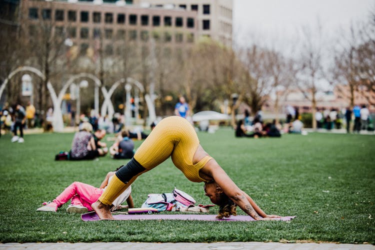 Black Woman Practicing Yoga In Park With Daughter