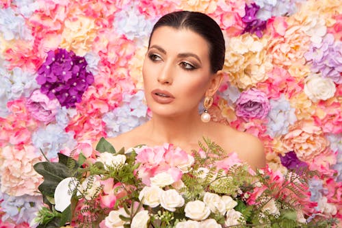 Elegant woman among bright blooming flowers