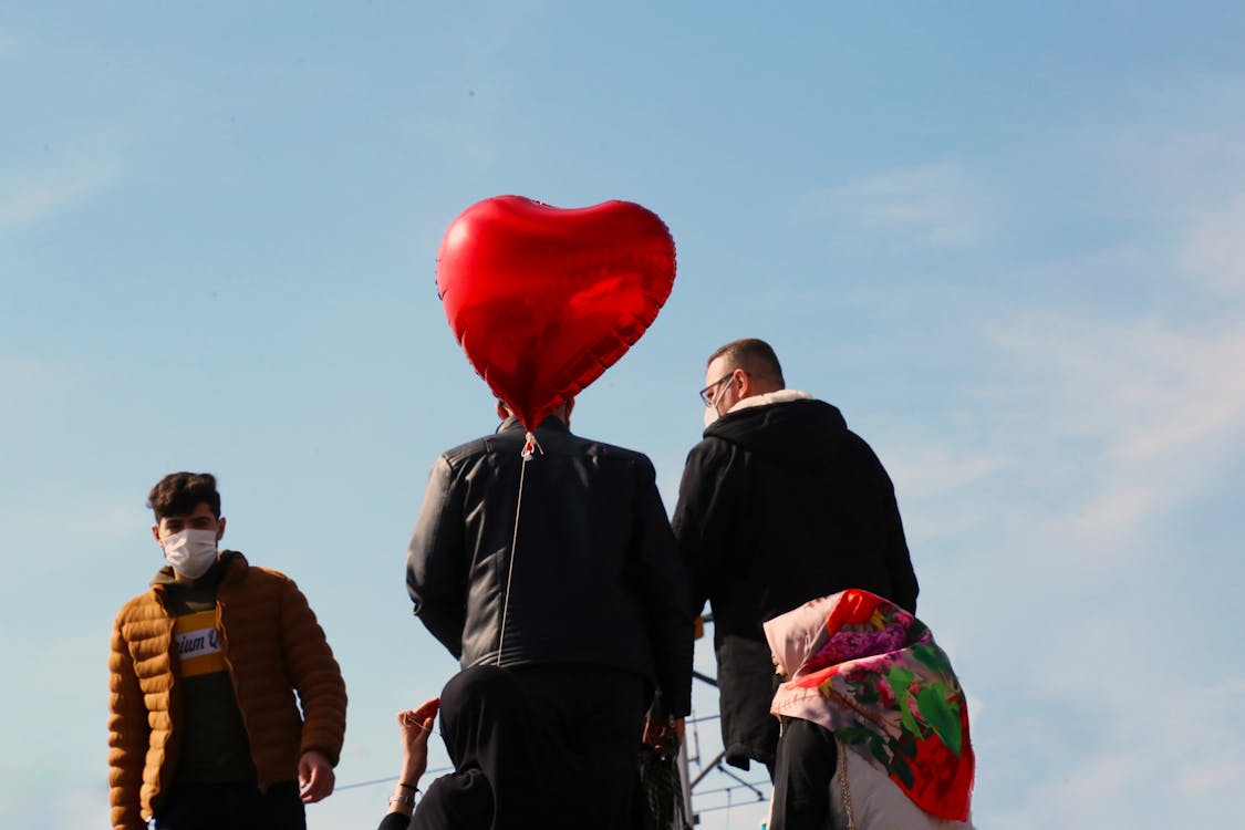 Free Back View of a Person Walking Near a Heart-Shaped Balloon Stock Photo