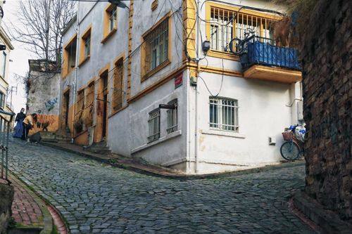 Free Cobblestone street featuring a vibrant building and parked bicycle, creating a rustic urban scene. Stock Photo