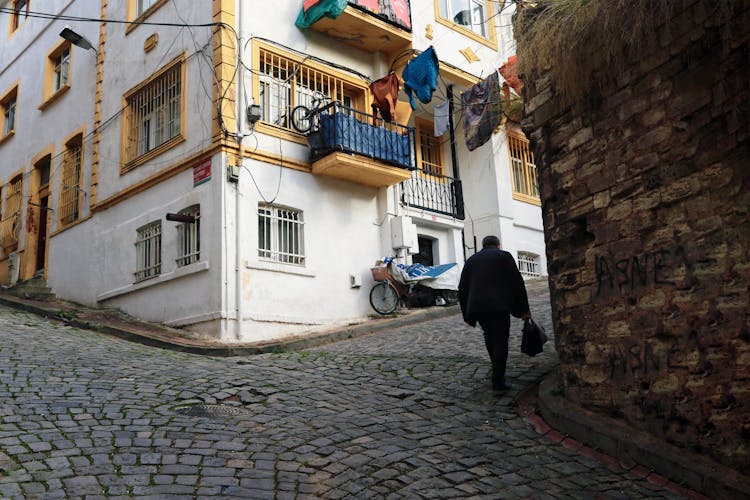 A Man Walking Uphill A Cobblestone Street