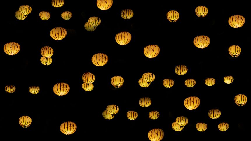 Glowing paper lanterns suspended against a night sky — photo by Min An on Pexels