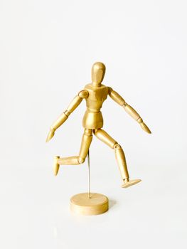 Wooden mannequin in a dynamic pose against a plain white background offering ample copy space.