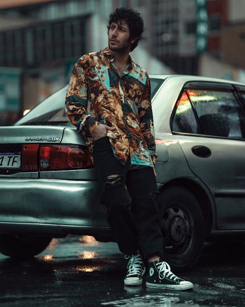 Free A Man in a Printed Shirt Leaning on a Car Stock Photo