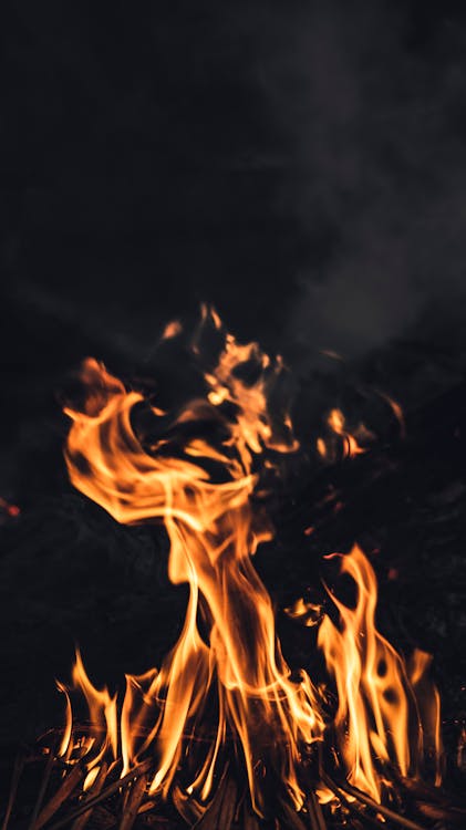 Burning flame against dark sky · Free Stock Photo