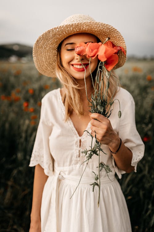 Free Charming woman in hat with flowers in meadow Stock Photo