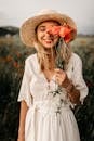 Charming woman in hat with flowers in meadow