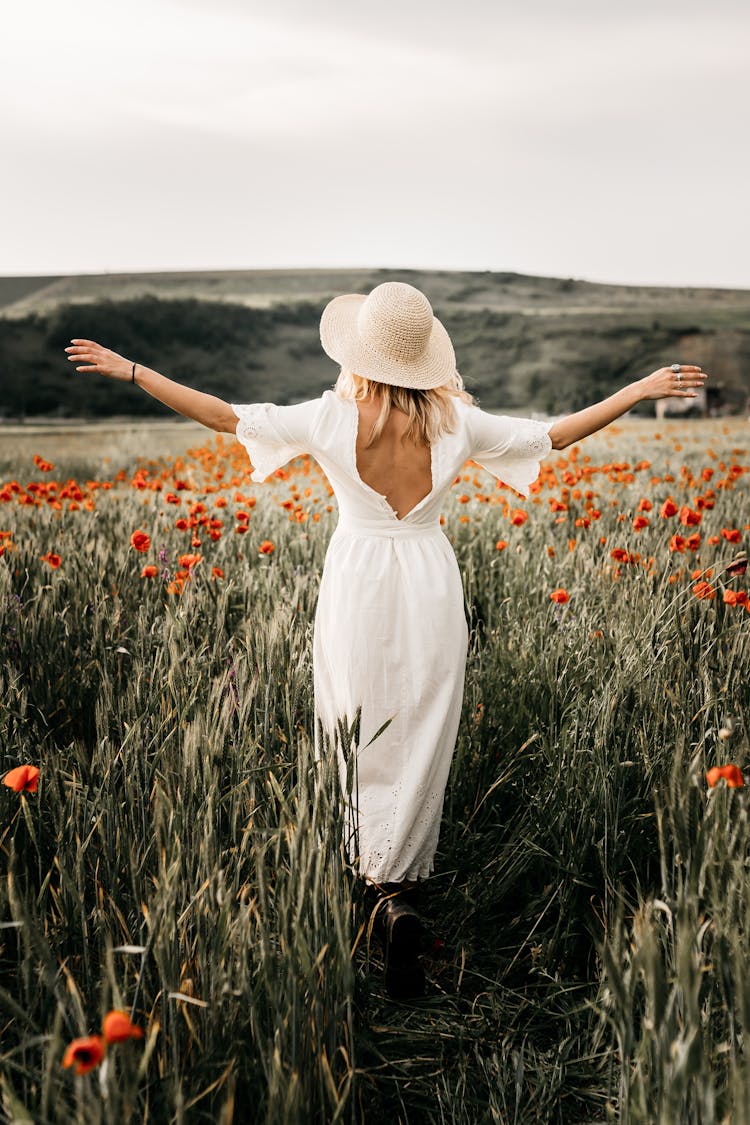 Elegant Woman In Hat Walking In Field With Flowers