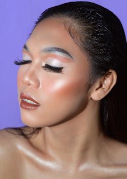Close-up portrait of a woman with creative makeup and eyes closed, set against a purple background.
