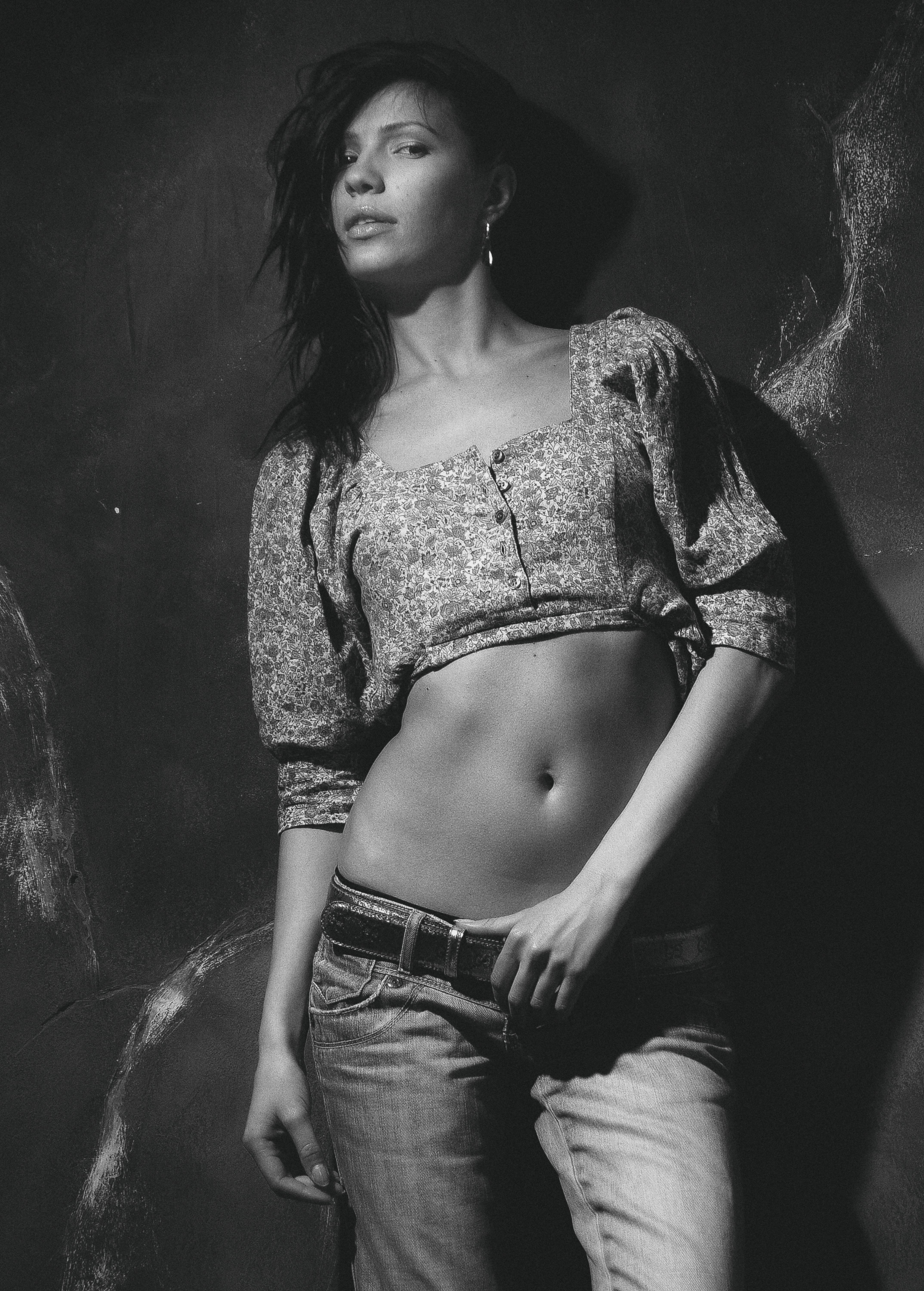 Elegant black and white portrait of a woman in a crop top and jeans, showcasing fashion and style.