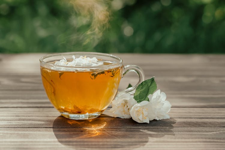 Cup Of Aromatic Jasmine Tea Served On Table In Garden