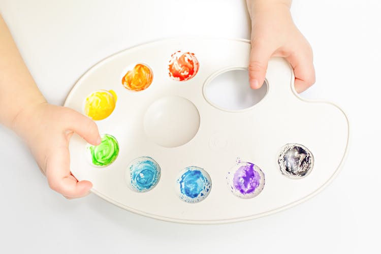 Crop Baby Mixing Multicolored Paint On Palette