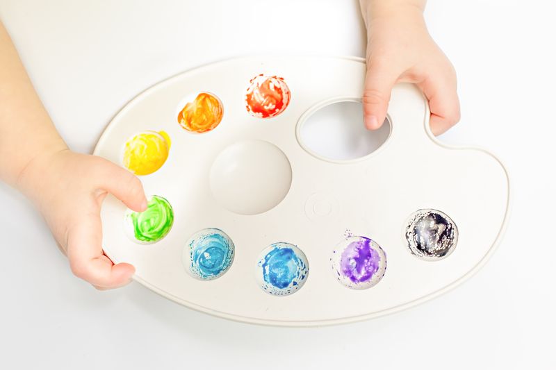 A child mixing paint colours on a palette
