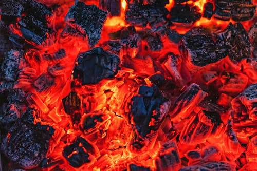 From above of bright orange hot coals placed in bonfire in evening time