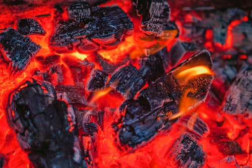 Textured background of charcoal with dry rugged surface burning fast in bright red fire