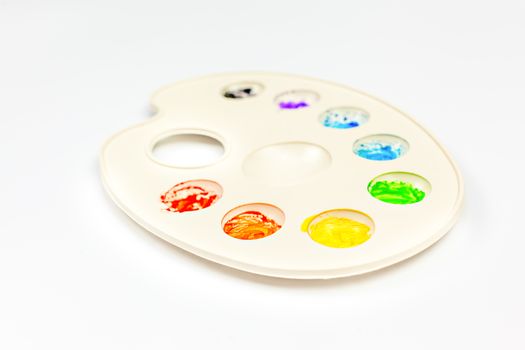 Palette with colorful paints on white background