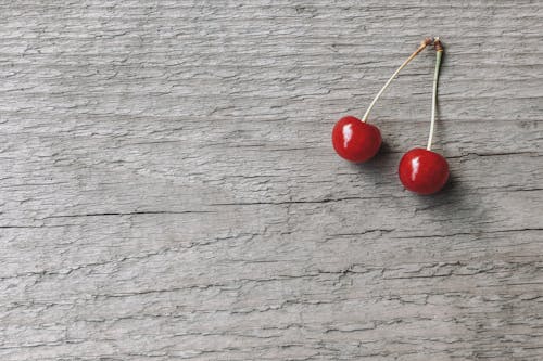 Overhead view of tasty fresh cherries with shiny peel and peduncles on rough wooden surface