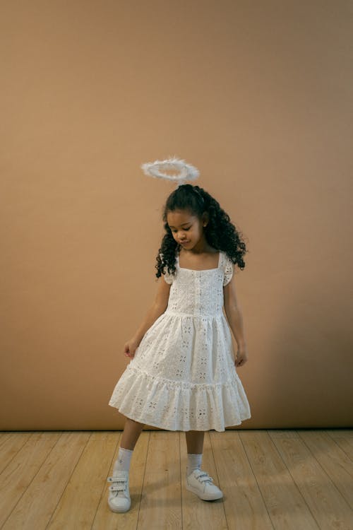 Cute black girl in angel costume in studio