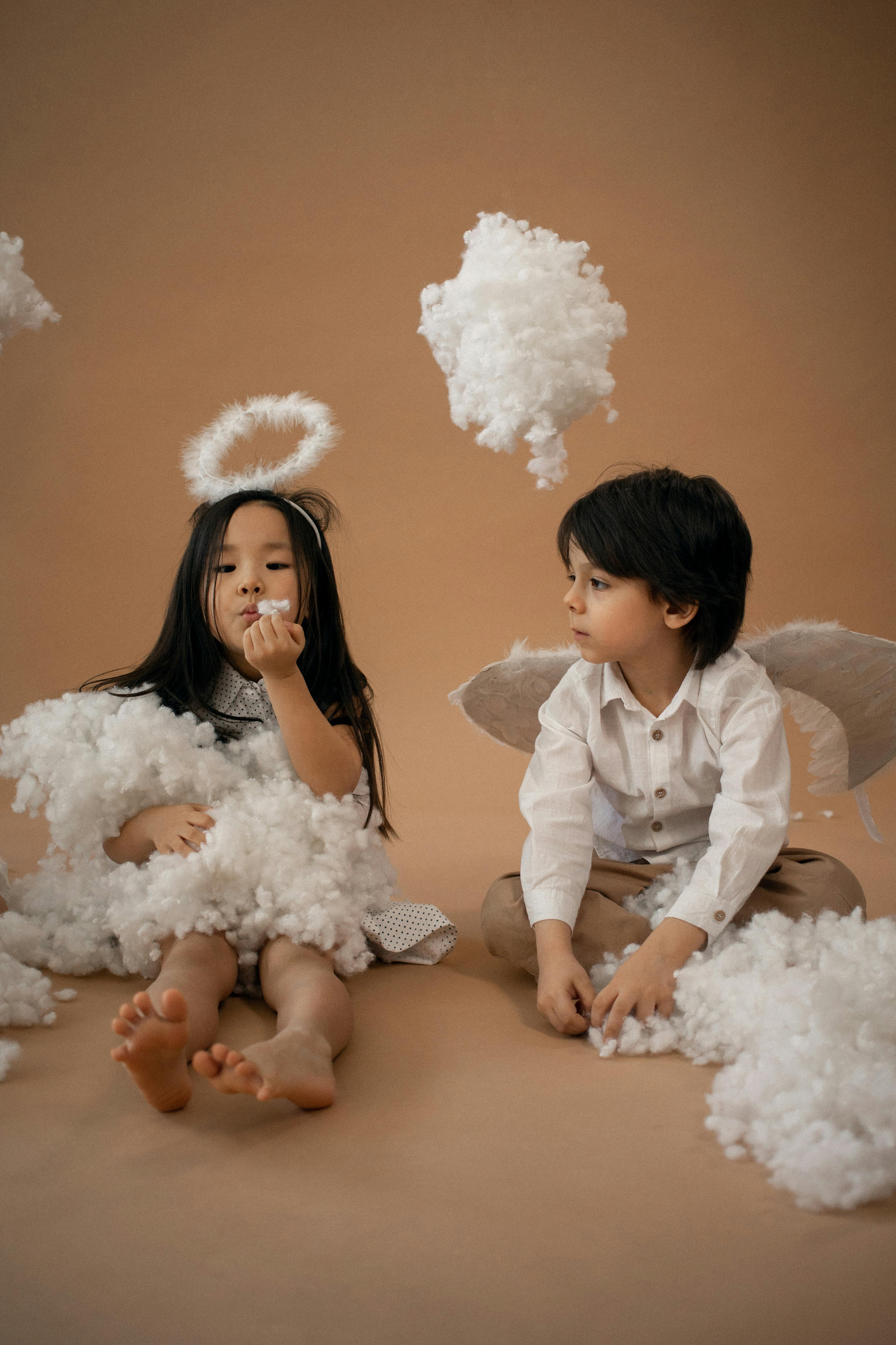 multiethnic children in angel costumes in studio with cotton wool