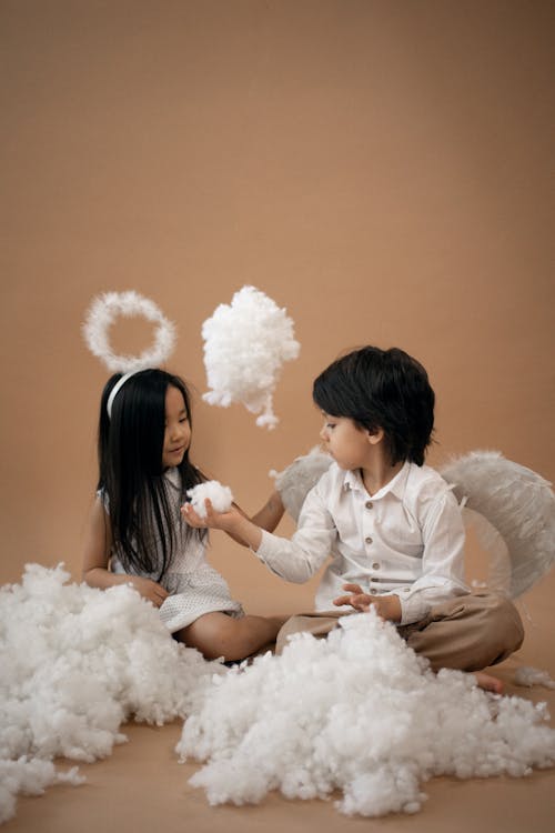 Diverse children in angel costumes playing with cotton