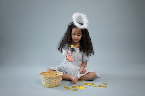 Free Content black girl in angel outfit playing with yellow stars Stock Photo