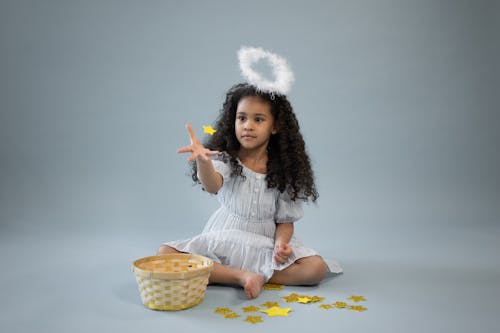 Free Focused black girl in angel costume catching decorative star Stock Photo