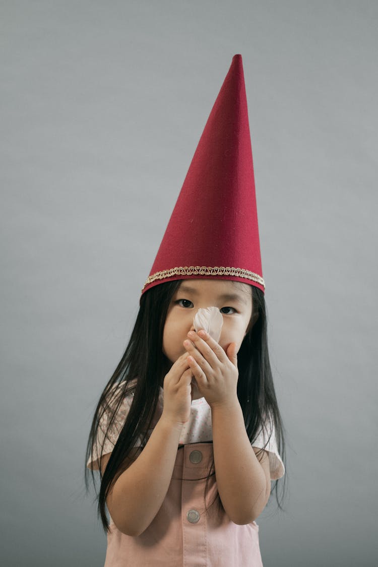 Cute Asian Girl In Gnome Cap With Feather In Hands