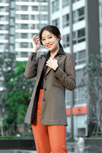 Portrait of a smiling woman in corporate attire with a blurred cityscape background.