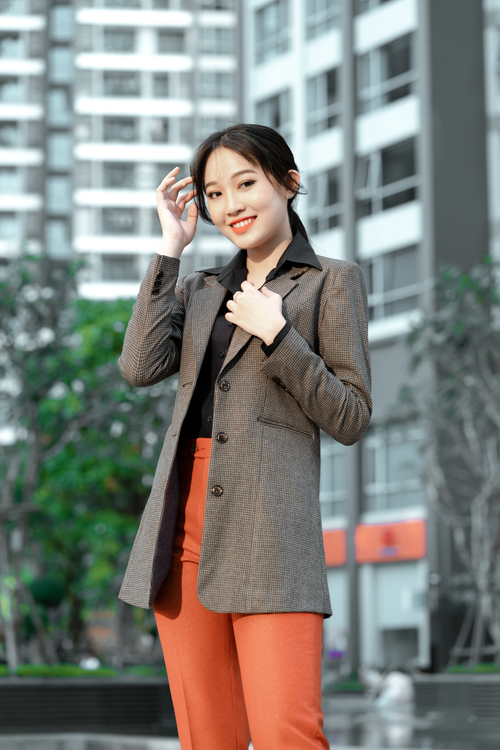 Free Portrait of a smiling woman in corporate attire with a blurred cityscape background. Stock Photo
