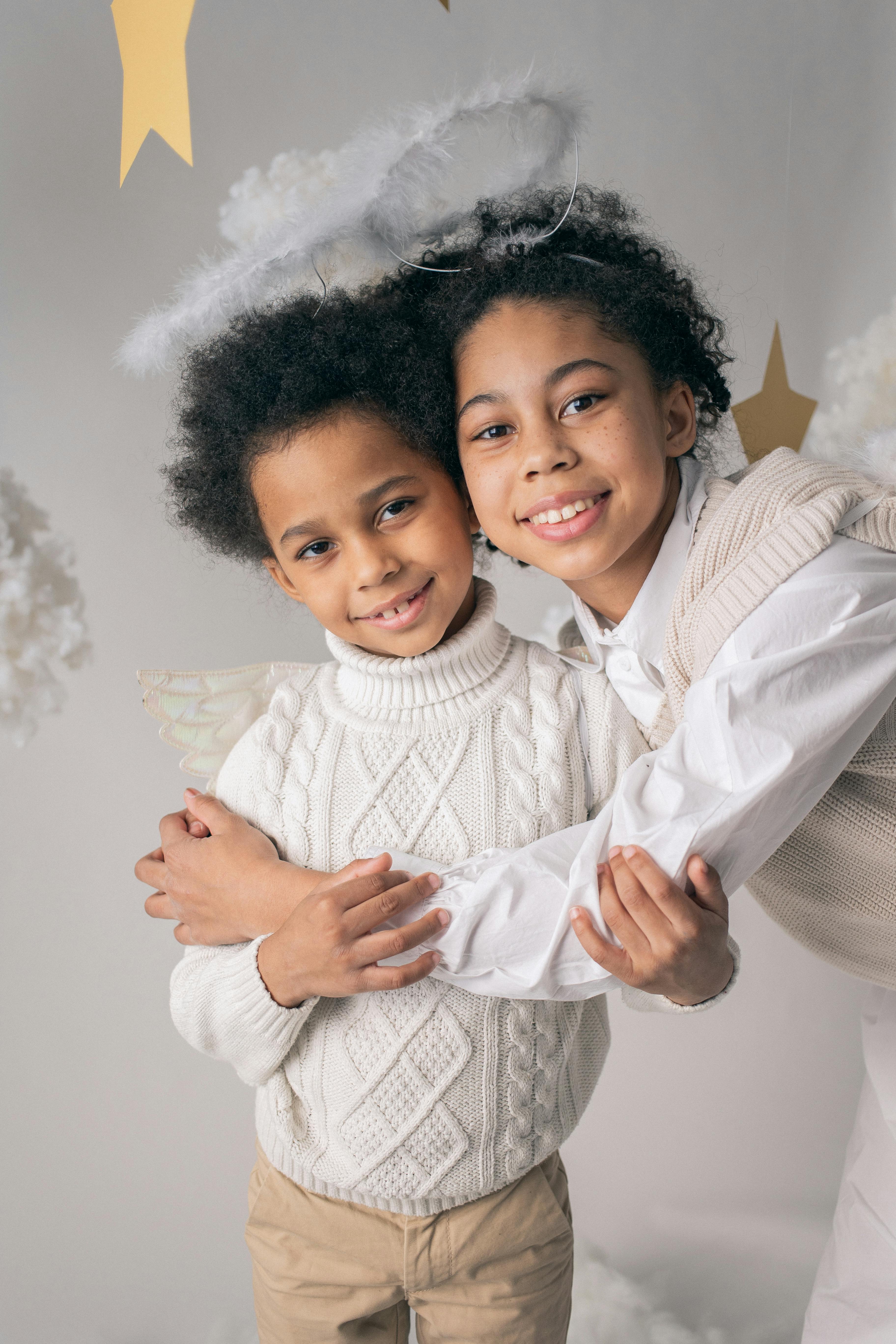 black girl embracing brother in angel costume